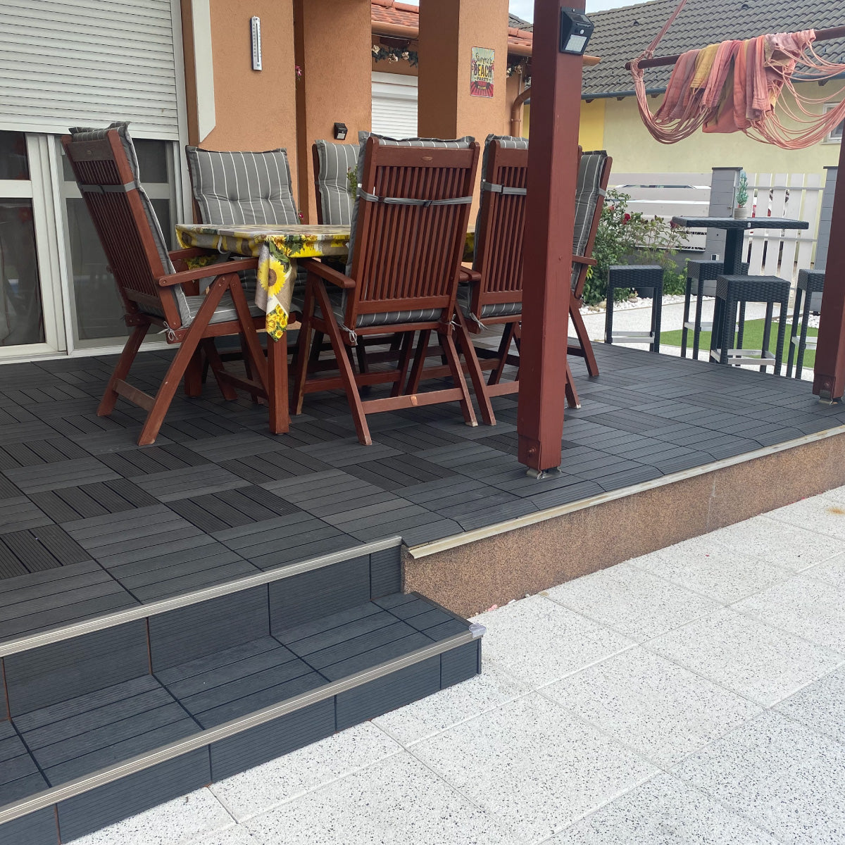 Outdoor patio area with dining set placed on charcoal patio tiles, creating a modern and durable flooring solution for terraces and balconies