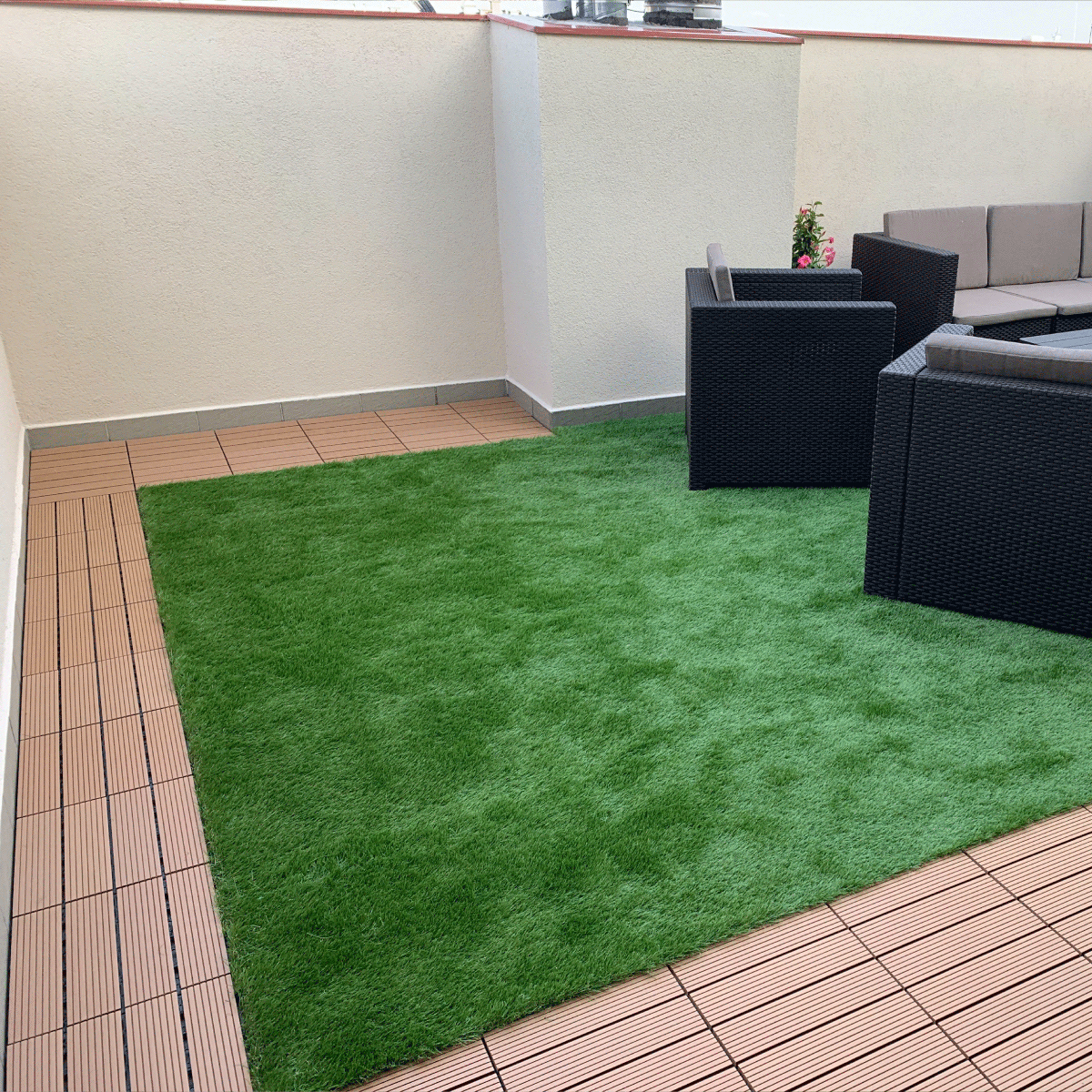 Modern rooftop terrace with teak patio tiles bordering a central grass tile area, creating a stylish and functional outdoor seating space with black wicker furniture