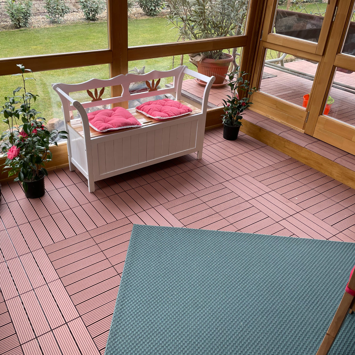 Indoor sunroom with brown patio tiles and white wooden bench, creating a warm and stylish flooring option for cozy seating areas 